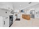 Modern kitchen with white cabinets, stainless steel fridge, center wooden island, and a stylish blue range hood at 556 Johns Pass Ave, Madeira Beach, FL 33708