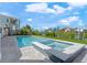 In-ground pool and hot tub bordered by green landscaping, houses, and blue sky at 556 Johns Pass Ave, Madeira Beach, FL 33708