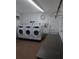 Functional laundry room with three washing machines, a utility sink, and folding table at 5725 80Th N St # 107, St Petersburg, FL 33709