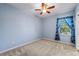 Cozy bedroom with a ceiling fan, carpet flooring, and a bright window with patterned curtains at 6732 Rocky Park St, Tampa, FL 33625