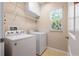 Bright laundry room featuring a modern washer and dryer, storage shelves, and a window at 6732 Rocky Park St, Tampa, FL 33625
