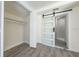 Bright bedroom featuring modern barn door to bathroom, closet, and gray wood flooring at 7322 Mako Dr, Hudson, FL 34667