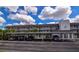 Three-story condo building features covered parking and well-maintained landscaping under a sunny sky with fluffy white clouds at 9815 47Th N Ave # 306, St Petersburg, FL 33708