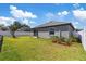 Well-maintained backyard featuring a lush lawn, white fence, and mature landscaping under a partly cloudy sky at 1050 Davis Heather Cir, Seffner, FL 33584