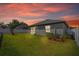 Sunset view of well-maintained backyard featuring a lush lawn, white fence, and mature landscaping at 1050 Davis Heather Cir, Seffner, FL 33584