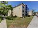 A well-maintained, light-yellow condo building featuring lush landscaping on a bright, sunny day at 14130 Rosemary Ln # 1201, Largo, FL 33774