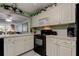 Charming kitchen featuring white cabinetry, black appliances, and bright decor at 14130 Rosemary Ln # 1201, Largo, FL 33774