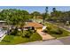 A single-story home with a brown roof, brick driveway, and lush green lawn surrounded by trees at 1591 N Dakota Ne Ave, St Petersburg, FL 33703