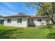 Backyard view showcasing the home's exterior with a lush green lawn and mature trees at 1651 Summit Way, Dunedin, FL 34698