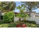 Landscaped single-story home featuring mature trees, green grass, and a stucco perimeter wall at 1651 Summit Way, Dunedin, FL 34698