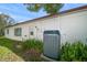 View of the home's exterior highlighting the lush landscaping, white exterior, and new AC unit at 1651 Summit Way, Dunedin, FL 34698