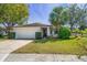 Inviting single-story home with a lush green lawn, mature trees, and attached two-car garage at 1651 Summit Way, Dunedin, FL 34698