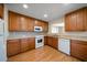 Well-lit kitchen featuring wood cabinets, white appliances, and a seamless mosaic backsplash at 1651 Summit Way, Dunedin, FL 34698