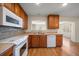 An open concept kitchen with wood cabinets, light countertops, white appliances, and hardwood floors at 1651 Summit Way, Dunedin, FL 34698