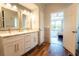 Bright bathroom with double vanity, modern fixtures, and wood-look tile flooring, leading to a bedroom at 1806 Lago Vista Blvd, Palm Harbor, FL 34685