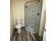 Bathroom featuring an enclosed glass shower, wood-look floor, and standard toilet at 1806 Lago Vista Blvd, Palm Harbor, FL 34685