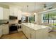 Bright kitchen with white cabinetry, stainless steel appliances, marble countertops, and a view of the living area at 1806 Lago Vista Blvd, Palm Harbor, FL 34685