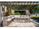 Outdoor pergola with comfortable seating around a cozy fireplace on a paved patio, perfect for entertaining at 1806 Lago Vista Blvd, Palm Harbor, FL 34685