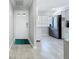 Hallway view of updated condo leading to kitchen area with stainless fridge, light gray walls and floors at 19029 Us Highway 19 N # 27A, Clearwater, FL 33764