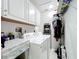 Functional laundry room with modern washer and dryer, overhead storage, and utility sink at 19029 Us Highway 19 N # 27A, Clearwater, FL 33764