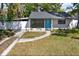 Charming home featuring a blue door, updated windows, and well-maintained landscaping enhancing curb appeal at 1908 E Mcberry St, Tampa, FL 33610