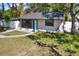 Cozy home featuring a blue door, fresh landscaping, and a well-manicured lawn, creating an inviting exterior at 1908 E Mcberry St, Tampa, FL 33610