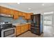 Bright kitchen featuring wood cabinetry, stainless steel appliances, and a stylish mosaic backsplash at 1908 E Mcberry St, Tampa, FL 33610