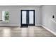 Bright foyer showcasing elegant wood-look tile flooring, black double-door entrance, and a window for natural light at 20 2Nd Se Ave, Lutz, FL 33549