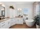 Bathroom with soaking tub, granite counters, white cabinets, framed mirrors, and wood-look tile flooring at 315 64Th St, Holmes Beach, FL 34217