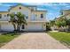Charming two-story home featuring a two-car garage, a balcony, a brick driveway, and lush, tropical landscaping at 315 64Th St, Holmes Beach, FL 34217