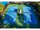 Aerial view of two blue tennis courts with green surrounding and a covered area with players present at 34024 White Fountain Ct, Wesley Chapel, FL 33545