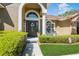 Inviting front entryway with a decorative door, arched window, and manicured landscaping at 3627 Cypress Meadows Rd, Tampa, FL 33624