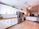 Spacious open-concept kitchen with stainless steel refrigerator, white cabinets, and attractive wood-look flooring at 39650 Us Highway 19 N # 411, Tarpon Springs, FL 34689
