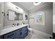 Bright bathroom with a navy blue vanity, arched window, and modern fixtures at 44 Martinique Ave, Tampa, FL 33606