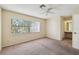 A spacious, bright bedroom featuring neutral walls and carpet, a ceiling fan, and a window with blinds at 440 Woods Landing Trl, Oldsmar, FL 34677