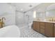 Bright bathroom with a soaking tub, tiled floors, double vanity with gold fixtures, and walk-in shower at 5011 S Elberon St, Tampa, FL 33611