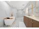 Luxurious bathroom featuring marble accents, a soaking tub, glass shower and vanity with gold fixtures at 5011 S Elberon St, Tampa, FL 33611