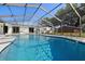 Sparkling in-ground pool with a screened enclosure, patio space, and lush greenery beyond at 5305 Coronet Rd, Plant City, FL 33566
