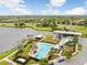 Aerial view of community amenities including a pool, lake access, lawns, clubhouse, and parking area in a lush landscaped setting at 5407 Tagalong Pl, Apollo Beach, FL 33572