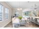 Bright dining area with a white table, modern chandelier, and large windows overlooking the outdoor space at 5407 Tagalong Pl, Apollo Beach, FL 33572