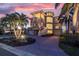 Elegant multi-story home featuring a spiral staircase, lush landscaping, and a brick driveway at sunset at 700 126Th Ave, Treasure Island, FL 33706