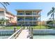 Stunning three-story waterfront property with multiple balconies, dock, and manicured lawn at 700 126Th Ave, Treasure Island, FL 33706