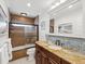 Bright bathroom features a tiled shower/tub, updated vanity with a granite countertop, and decorative mosaic tile backsplash at 108 24Th St, Belleair Beach, FL 33786
