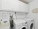 Bright laundry room features modern washer and dryer with overhead cabinets, and a utility sink at 108 24Th St, Belleair Beach, FL 33786