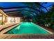 Beautiful screened pool illuminated at night surrounded by lush tropical landscaping at 11505 Gibralter Pl, Temple Terrace, FL 33617