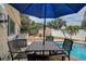 Backyard patio featuring a table, chairs, umbrella and in-ground pool at 12299 91St N Ave, Seminole, FL 33772