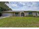 Charming home features a well-manicured lawn, stone accents, and an arched entryway leading to a white front door at 12299 91St N Ave, Seminole, FL 33772