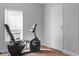 A black exercise bike in a room with gray walls, a window, brown carpet, and a white door at 12720 Four Oaks Rd, Tampa, FL 33624