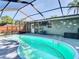 Screened-in outdoor kidney-shaped pool with patio and view of license plates on the house at 15536 George Blvd, Clearwater, FL 33760