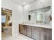 This bathroom features a dual sink vanity with granite countertop, a window and ensuite access at 16625 Goose Ribbon Pl, Wimauma, FL 33598